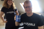 Two podcast listeners showing off their Unusable Podcast merchandise, including a t-shirt and mug